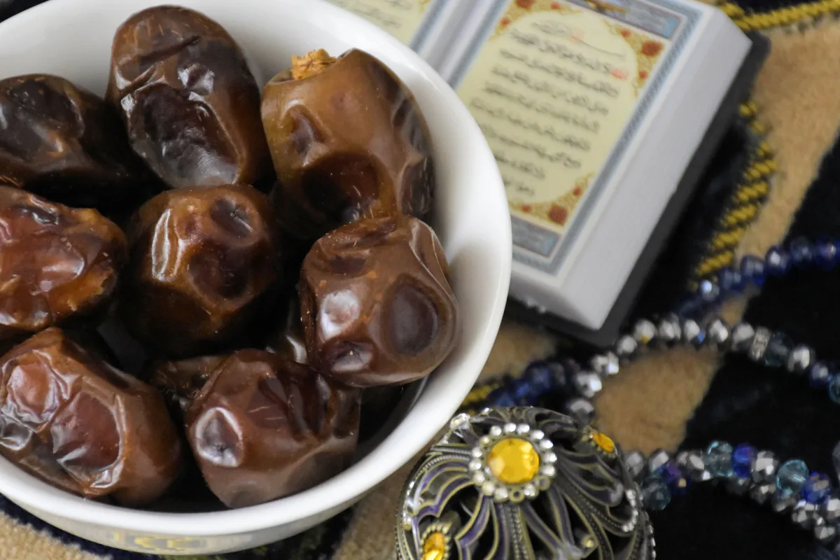 Dattes, figues sèches, raisins secs et abricots secs dans des coupelles en céramique sur une planche en bois